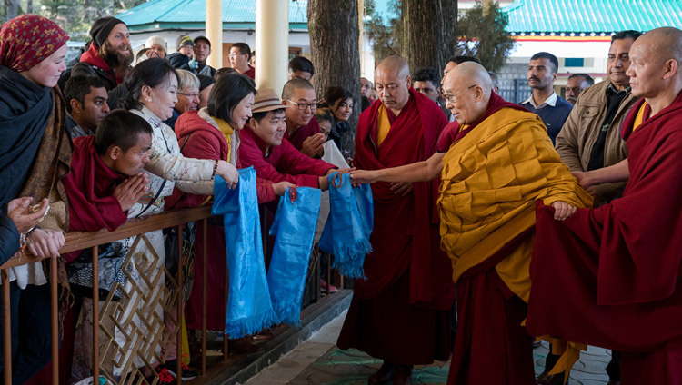 Его Святейшество Далай-лама приветствует верующих, направляясь в главный тибетский храм в начале второго дня учений. Фото: Тензин Чойджор (офис ЕСДЛ)