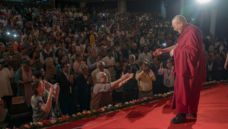 Его Святейшество Далай-лама приветствует слушателей, поднявшись на сцену центра исполнительских искусств Индийской телевизионной академии. Фото: Тензин Чойджор (офис ЕСДЛ)
