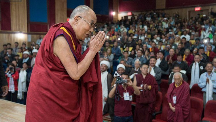 Его Святейшество Далай-лама приветствует слушателей, поднявшись на сцену в начале семинара «Гармония в местном сообществе – залог мира во всем мире», организованного в Центральном институте буддологии. Фото: Тензин Чойджор (офис ЕСДЛ)