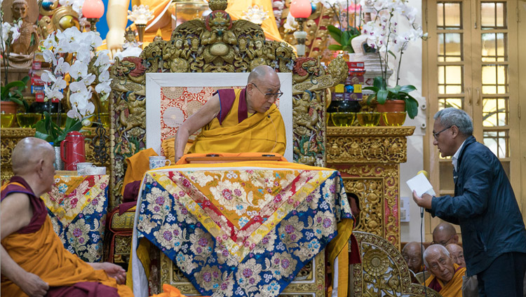 Переводчик на английский язык зачитывает Его Святейшеству Далай-ламе вопросы слушателей во время перерыва между сессиями учений. Фото: Тензин Пунцок (офис ЕСДЛ)