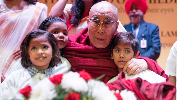 Его Святейшество Далай-лама фотографируется с детьми, получающими помощь благотворительного фонда «Улыбка», перед началом лекции в конференц-центре Национального объединенного союза Индии. Фото: Тензин Чойджор (офис ЕСДЛ)