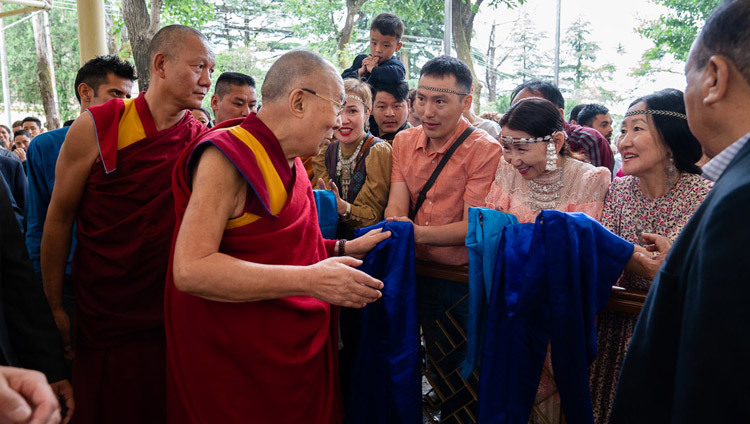 Направляясь на конференцию с российскими учеными и буддийскими учеными-философами, Его Святейшество Далай-лама приветствует верующих, собравшихся во дворе главного тибетского храма. Фото: Тензин Чойджор.