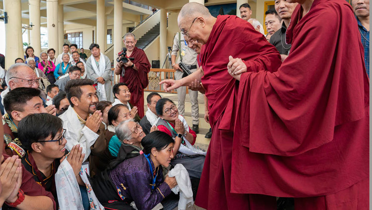 Его Святейшество Далай-лама приветствует слушателей, покидая главный тибетский храм по завершении встречи с участниками Международной конференции, посвященной подходу Срединного пути. Фото: Тензин Чойджор.