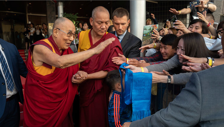 Направляясь утром в зал «Сконто», Его Святейшество Далай-лама приветствует верующих, собравшихся у отеля. Фото: Тензин Чойджор.