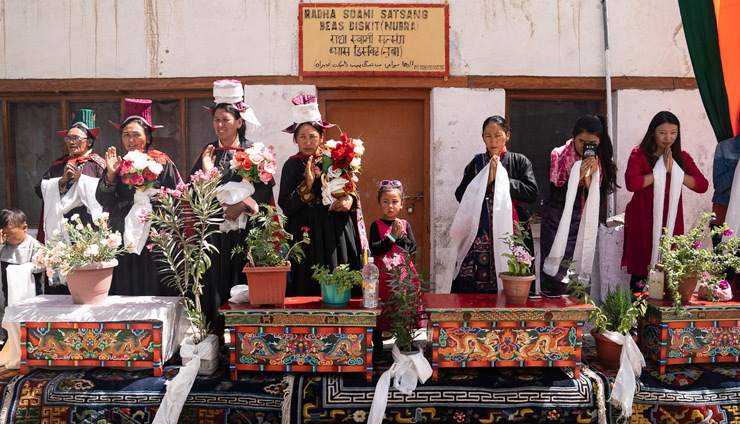 Местные жители стоят у дверей своих домов, выставив на улицы резные столики с цветами в горшках, чтобы поприветствовать Его Святейшество Далай-ламу. Фото: Тензин Чойджор.