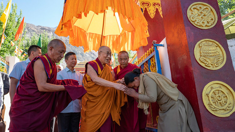 Направляясь на церемонию открытия Великих летних диспутов, Его Святейшество Далай-лама приветствует сотрудницу службы безопасности. Фото: Тензин Чойджор.