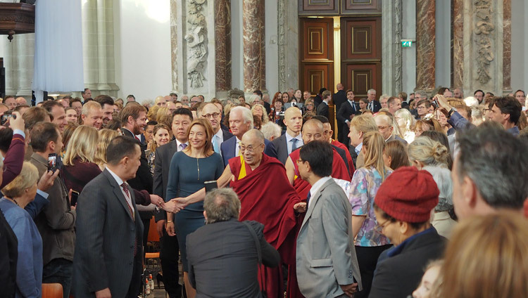 Директор церкви Ньиве керк Кателин Броэрс сопровождает Его Святейшество Далай-ламу, который по прибытии приветствует собравшихся слушателей. Фото: Джереми Рассел.