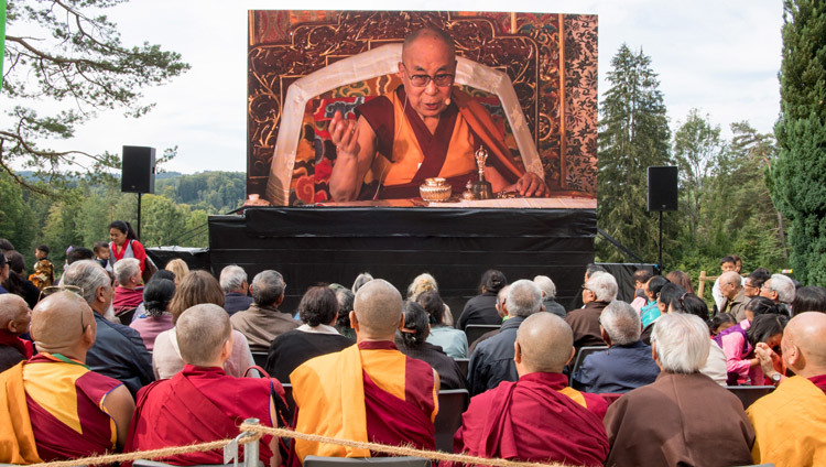 Слушатели, собравшиеся на площадке перед храмом, смотрят трансляцию выступления Его Святейшества Далай-ламы на церемонии празднования 50-летия Тибетского института в Риконе. Фото: Мануэль Бауэр.