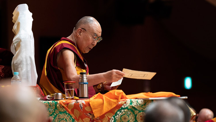 Его Святейшество Далай-лама читает строфы текста во время первого дня учений в конференц-центре «Пасифико Йокогама». Фото: Тензин Чойджор.