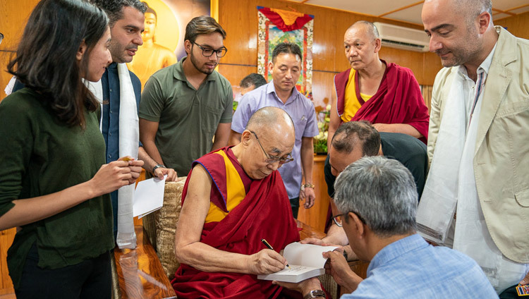 По окончании встречи Его Святейшество Далай-лама подписывает книгу для иранских гостей. Фото: Тензин Чойджор.