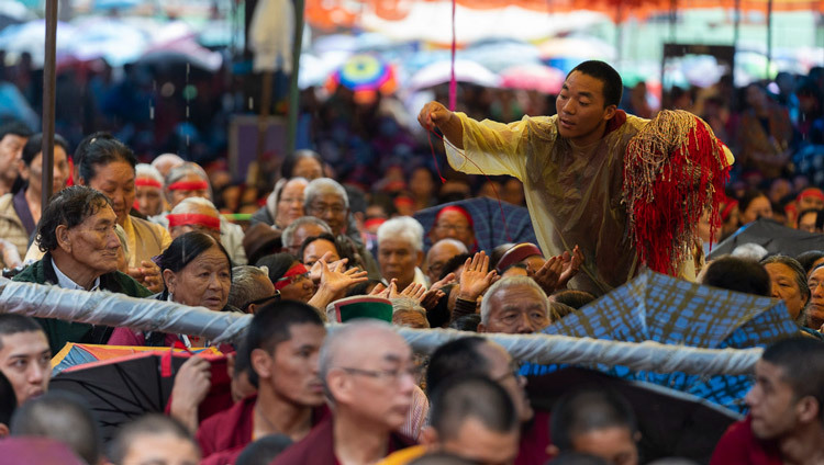 Волонтер раздает защитные ритуальные веревочки во время посвящения Махакаруники Локешвары, даруемого Его Святейшеством Далай-ламой. Фото: Тензин Чойджор (офис ЕСДЛ).