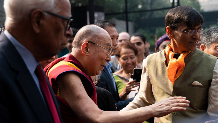 Покидая сцену по завершении лекции в международном центре Индии, Его Святейшество Далай-лама приветствует слушателей. Фото: Тензин Чойджор (офис ЕСДЛ).