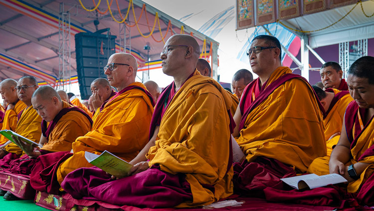 Старшие монахи, сидящие на сцене, следят за текстом во время учений Его Святейшества Далай-ламы. Фото: Тензин Чойджор.