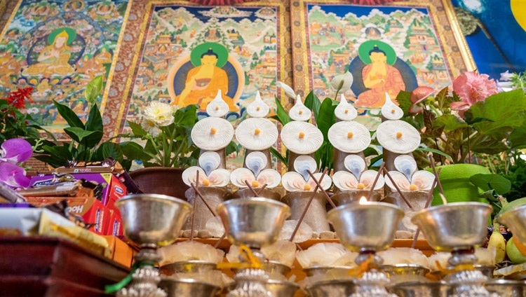 Подношения, стоящие у алтаря позади Его Святейшества Далай-ламы во время первого дня учений по произведению Атиши «Светоч на пути к Пробуждению». Дхарамсала, штат Химачал-Прадеш, Индия. 13 июля 2021 г. Фото: дост. Тензин Джампхел.