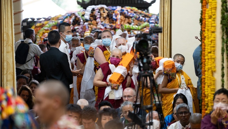Члены Фонда Поддержания Махаянской Традиции (ФПМТ) входят в главный тибетский храм с подношениями, приготовленными для Его Святейшества Далай-ламы (на заднем фоне виднеется множество подношений, которые будут раздаваться всем участникам церемонии). Дхарамсала, штат Химачал-Прадеш, Индия. 24 мая 2023 г. Фото: Тензин Чойджор (офис ЕСДЛ).