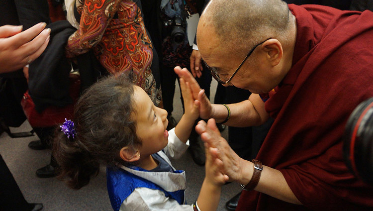 Его Святейшество Далай-лама приветствует маленькую девочку во время своего визита в Ванкувер, Британская Колумбия, Канада, 22 октября 2014 года. (Фото: Джереми Рассел, офис ЕСДЛ)o by Jeremy Russell/OHHDL)